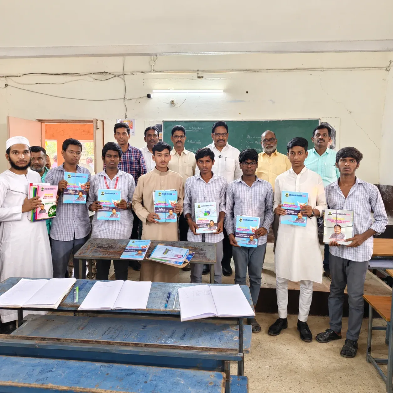 Yennam Srinivas Reddy stands with students holding QR code digital learning books in a classroom