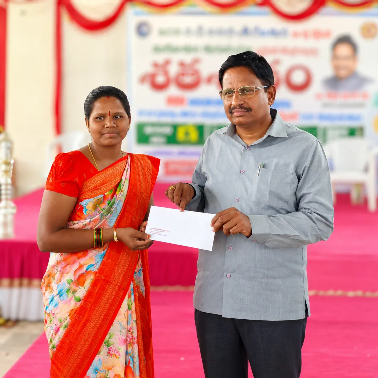 Yennam Srinivas Reddy hands an envelope to a teacher at a Shata Shatam programme